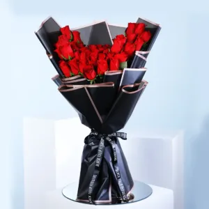 he image shows a bouquet of red roses wrapped in black paper with a gold ribbon.