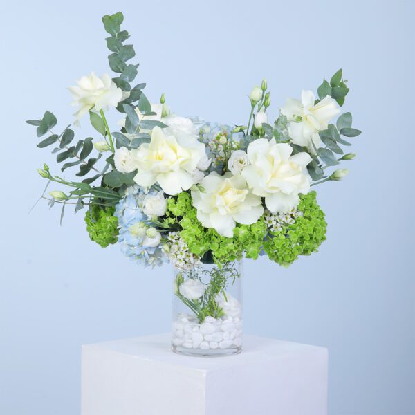 A beautifully arranged vase holds a mix of white and green flowers, creating a serene and fresh floral display.