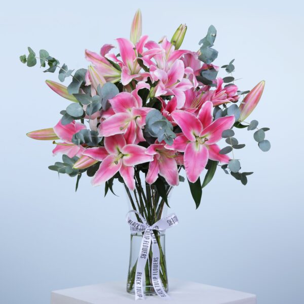 A decorative vase containing pink lilies and eucalyptus, highlighting the beauty of nature in a stylish display.