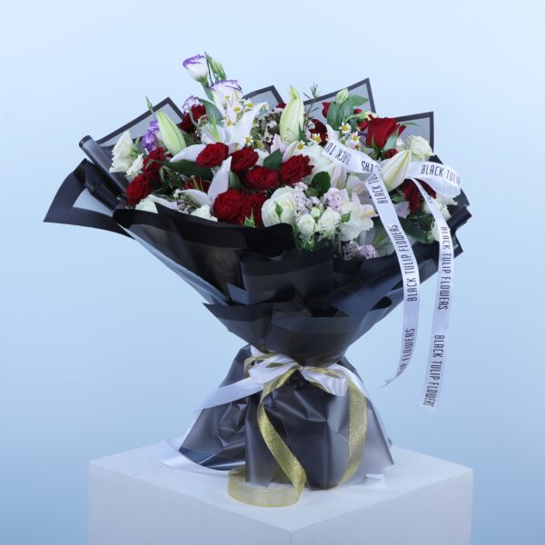 Bouquet of red roses, Casablanca lilies, white and purple blooms, wrapped in white and gold ribbon.