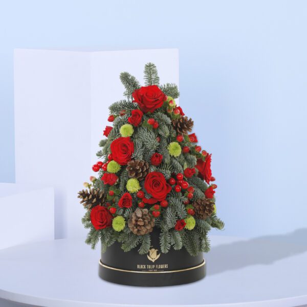 A festive mini Christmas tree arrangement with red roses, greenery, and ornaments.